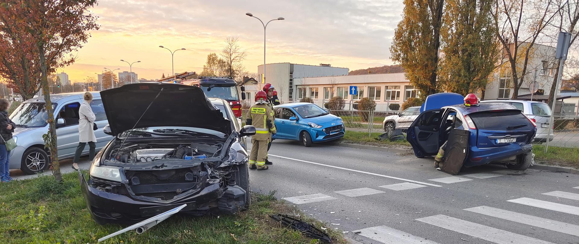 Zdjęcie przedstawia ulicę Krakowską w Kielcach: po dwóch stronach jezdni stoją uszkodzone samochody, na drodze znajdują się ratownicy.