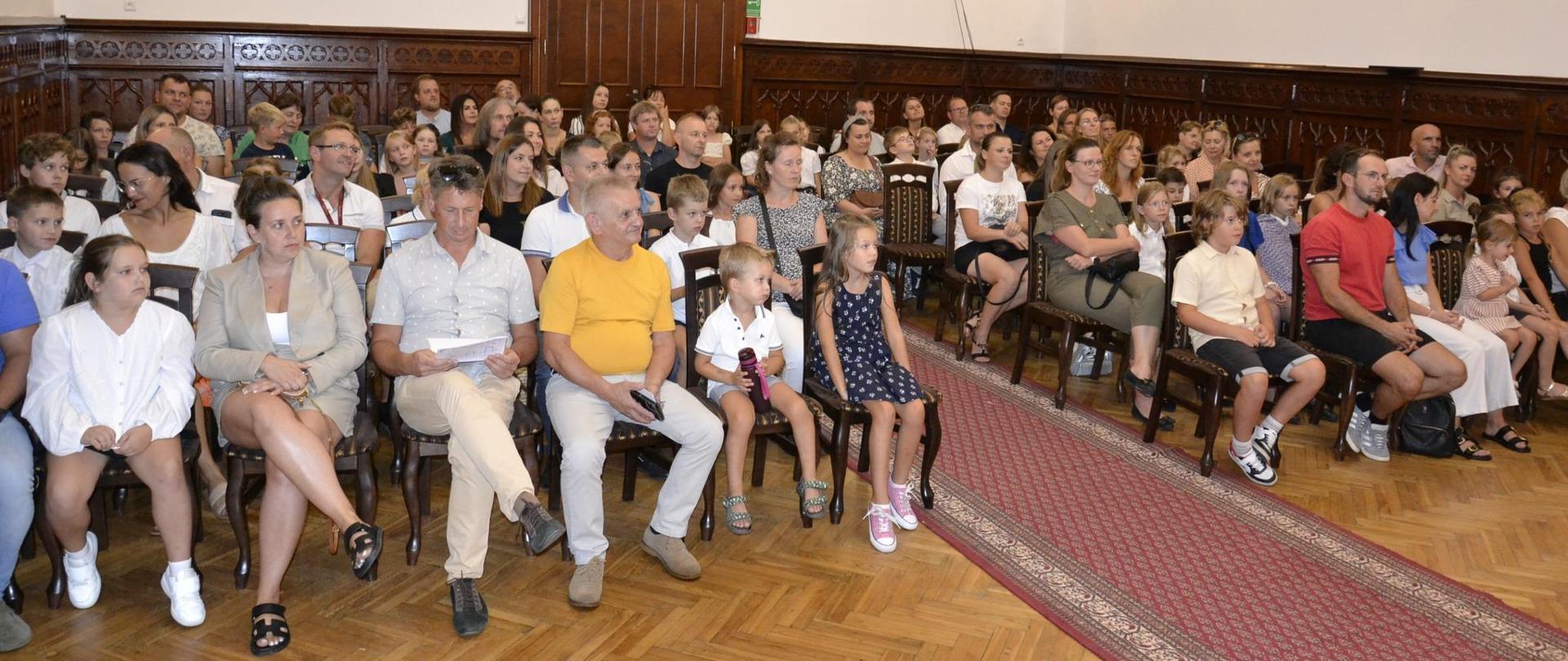 rodzice i uczniowie podczas rozpoczęcia roku szkolnego na sali królewskiej PSM Mielec