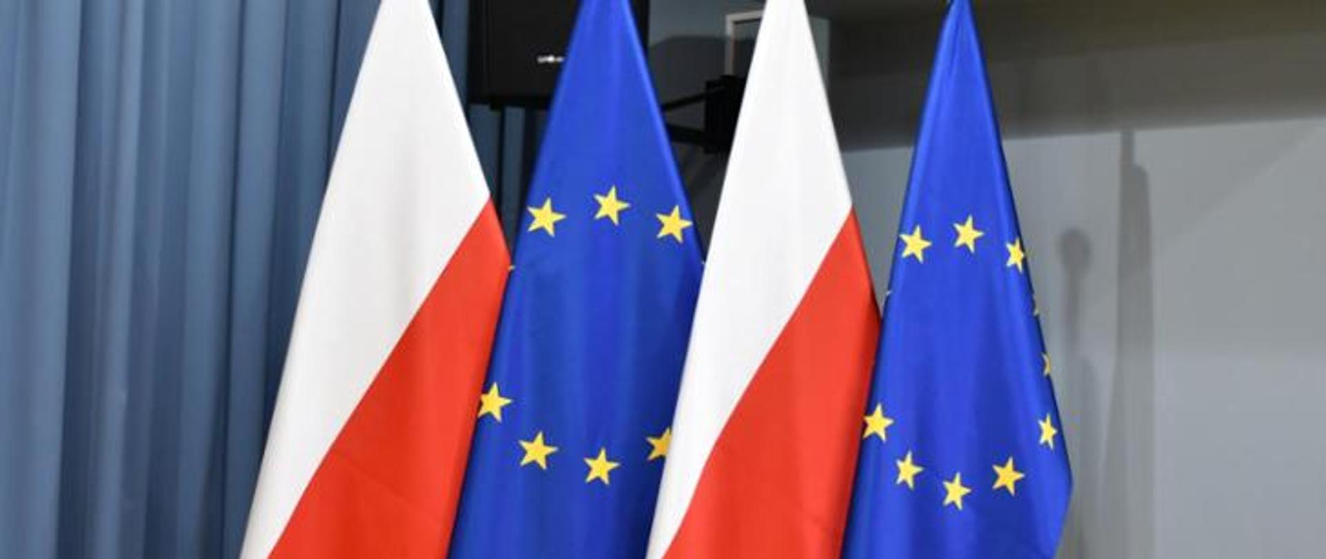 Zdjęcie przedstawiające cztery flagi Polski i Unii Europejskiej ustawione naprzemiennie. 