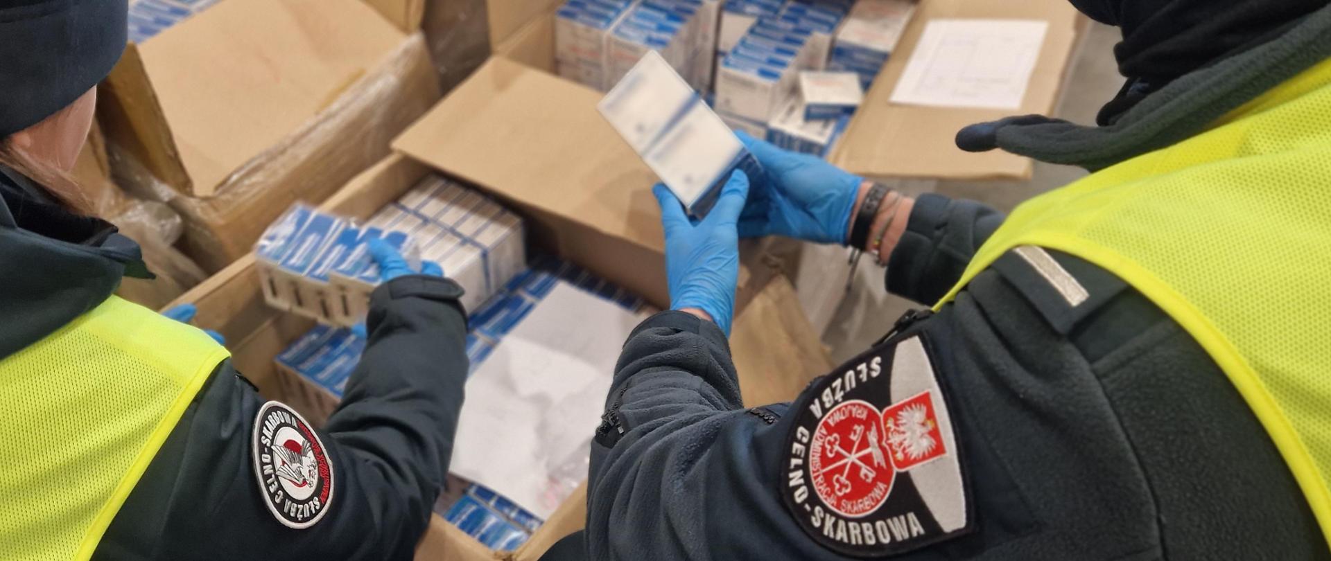 Funkcjonariusze Służby Celno-Skarbowej podczas przeglądania kartonów z nielegalnymi środkami farmaceutycznymi