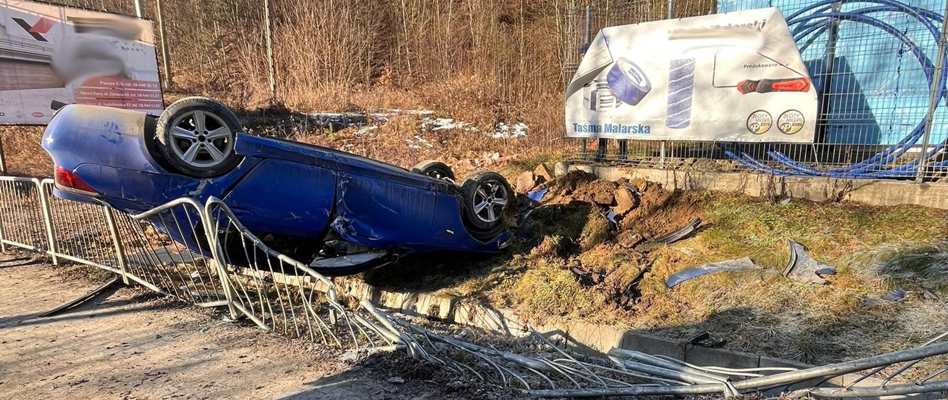 Samochód osobowy na dachu na przydrożnych barierkach