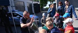 Dzieci próbują przesunąć policjanta osłaniającego się tarczą