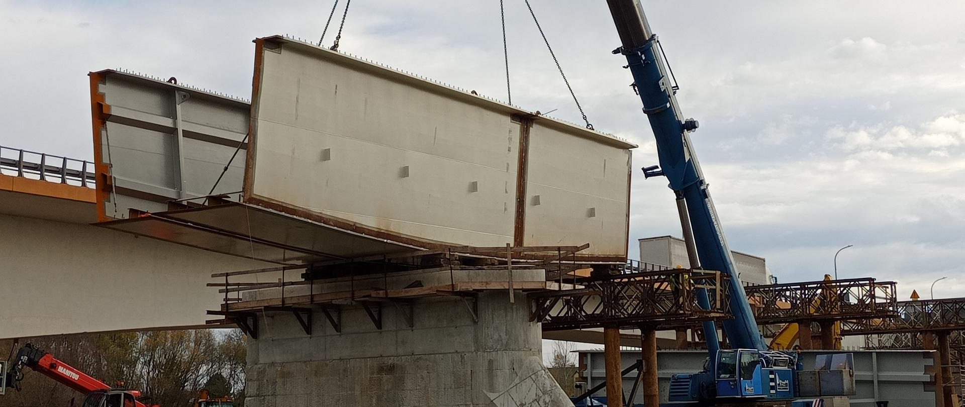 Budowa mostu w Sandomierzu - umieszczanie stalowego elementu konstrukcji na betonowej podporze z pomocą dźwigu. 