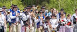 Sceneria plenerowa. Zespół składający się z uczniów szkoły muzycznej grają na instrumentach : trąbkach, fletach, klarnetach ubrani w stroje góralskie. Zespół znajduje się na łące. 