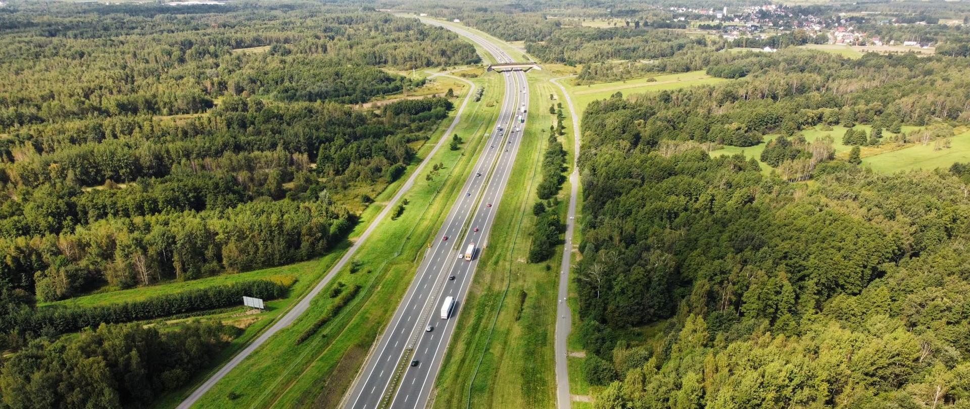 Autostrada A4 Kraków Tarnów, zdjęcie zrobione z lotu ptaka, A4 biegnie wśród terenów leśnych, w oddali po prawej zabudowania