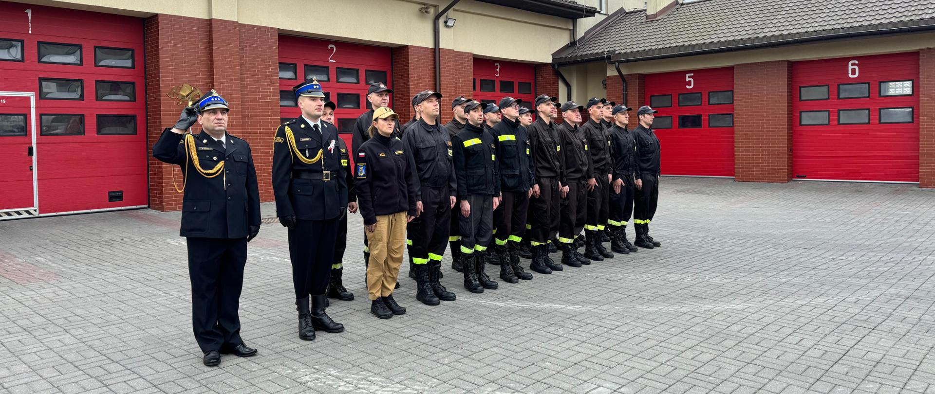 Na placu jednostki ratowniczo-gaśniczej w Rypinie pododdział strażaków oddaje honor podczas podnoszenia flagi państwowej na maszt. Pododdziałem dowodzi zastępca dowódcy jednostki ratowniczo-gaśniczej kapitan Dariusz Kuciński.