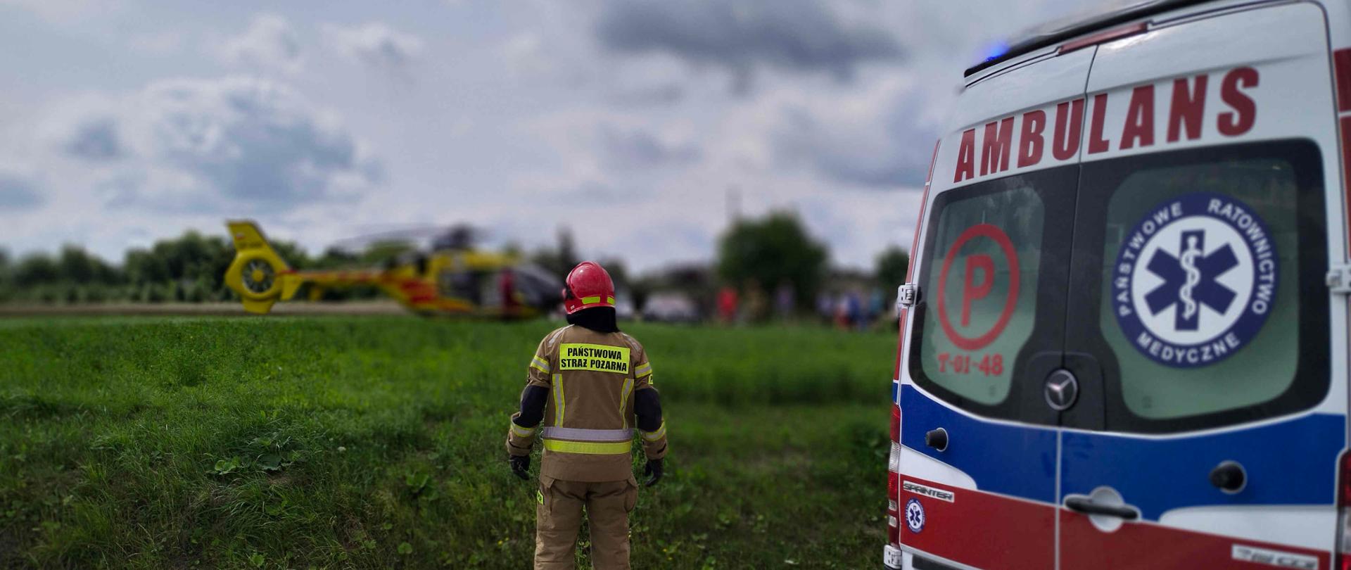 Zdjęcie przedstawia strażaka – ratownika zabezpieczającego miejsce lądowania śmigłowca LPR