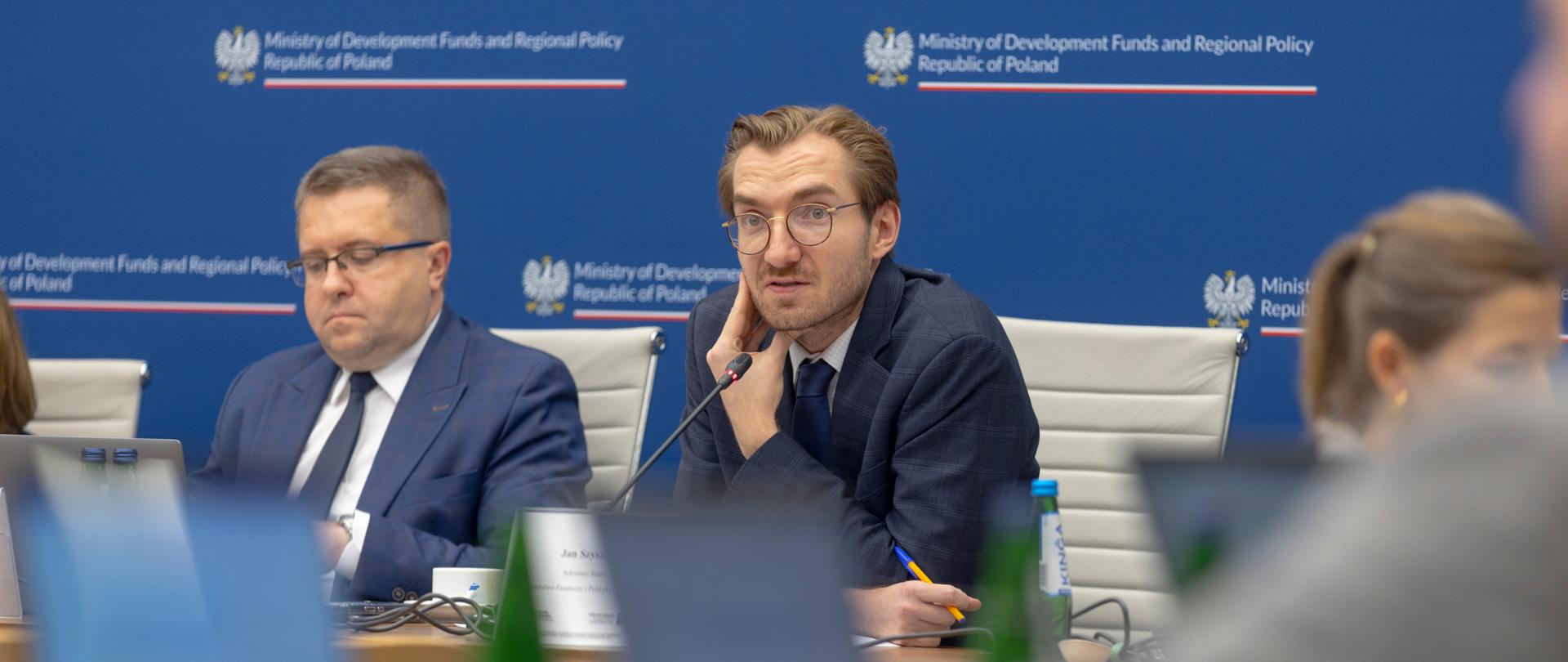 Wiceminister Jan Szyszko siedzi z grupą osób przy stole w sali konferencyjnej