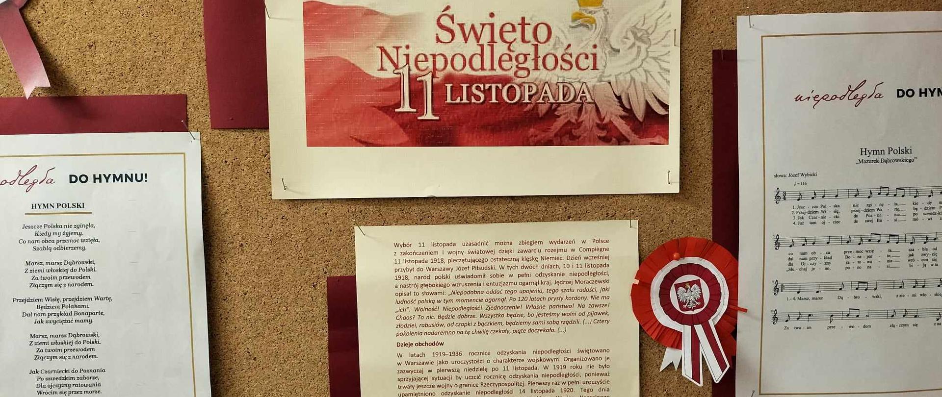 Na tablicy korkowej w centralnym miejscu, na górze kartka w kolorze biało - czerwonym, z orłem w koronie i napisem Święto niepodległości 11 listopada, po lewej stronie zdjęcia kartka z tekstem hymnu polskiego, zaś po prawej stronie zdjęcia kartka z nutami hymnu polskiego.