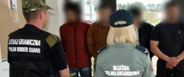 Funkcjonariusze KAS i SG przy zatrzymanych migrantach