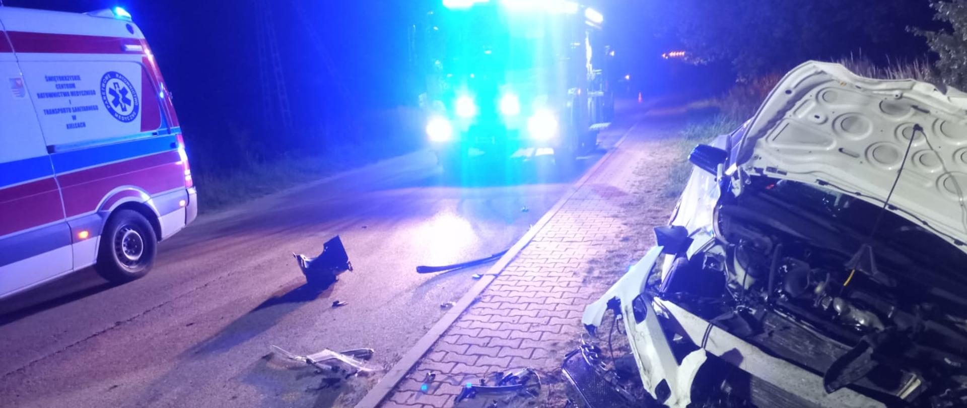 Skutki wypadku - po prawej rozbity samochód w środków wóz strażacki po lewej ambulans, noc, światła ostrzegawcze pojazdów.