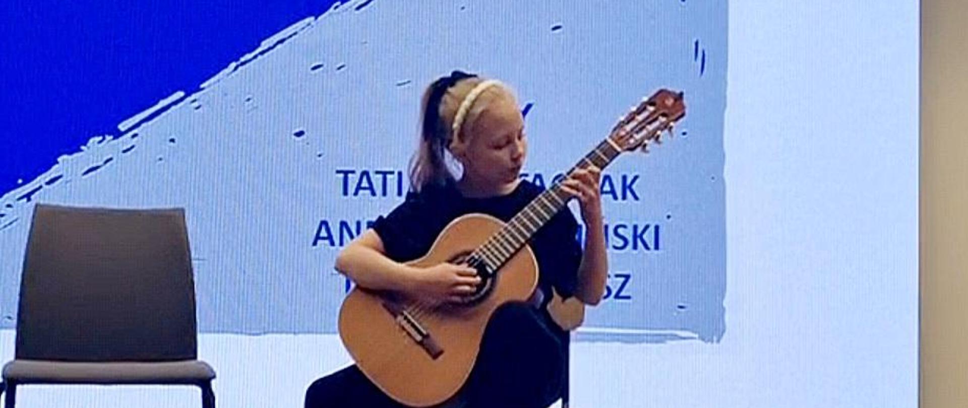 Zdjęcie uczennicy grającej na gitarze podczas prezentacji konkursowej