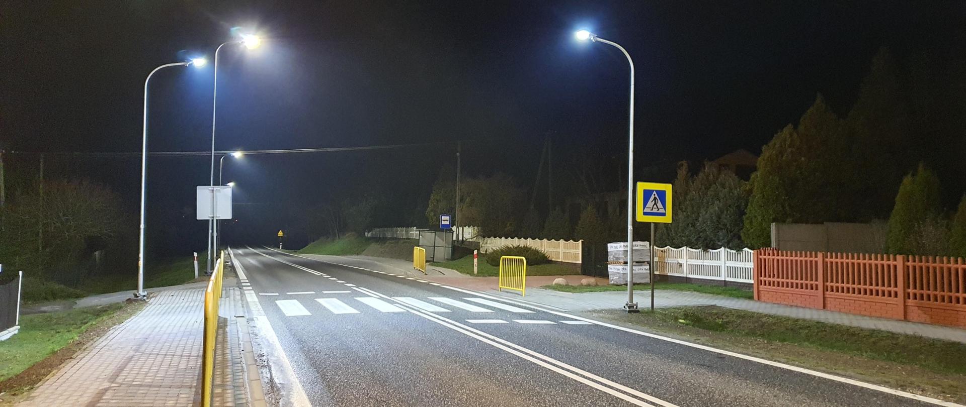 Przejście dla pieszych - oznakowanie poziome - białe pasy na jezdni, latarnie oświetlające przejście w nocy, znak drogowy "przejście dla pieszych" 