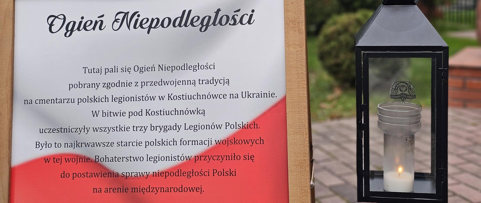 Zdjęcie wykonane przed komendą powiatową Państwowej Straży Pożarnej w Mielcu. Na pierwszym planie widać baner informacyjny oraz świecę z ogniem niepodległości głównym wejściem do komendy powiatowej Państwowej Straży Pożarnej w Mielcu.