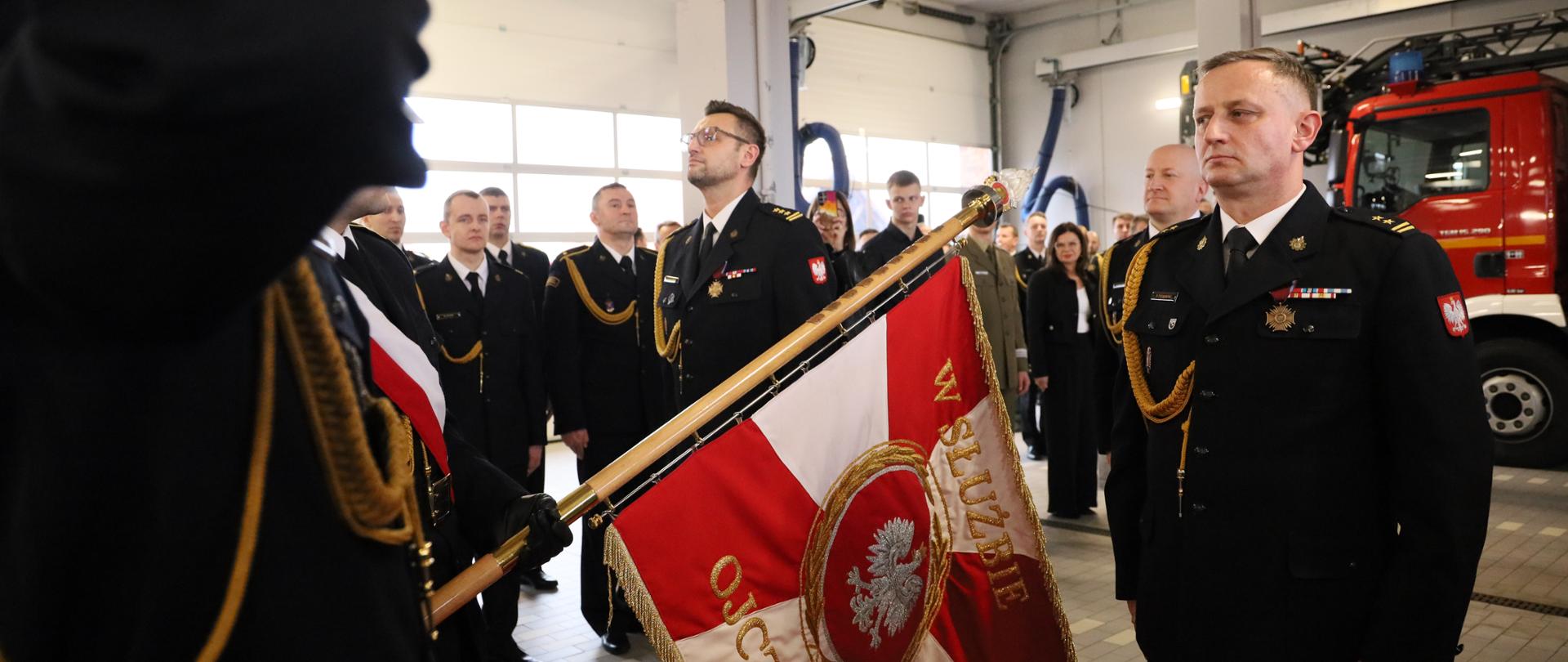 Na zdjęciu po lewej stronie sztandaru starszy brygadier Piotr Tkaczyński zdający obowiązki Komendanta Powiatowego Państwowej Straży Pożarnej w Świeciu oraz po prawej stronie sztandaru brygadier Paweł Puchowski przyjmujący obowiązki Komendanta Powiatowego Państwowej Straży Pożarnej w Świeciu w obecności Kujawsko-Pomorskiego Komendanta Wojewódzkiego Państwowej Straży Pożarnej starszego brygadiera Rafała Świechowicza. W tle zaproszeni goście oraz funkcjonariusze Komendy Powiatowej Państwowej Straży Pożarnej w Świeciu