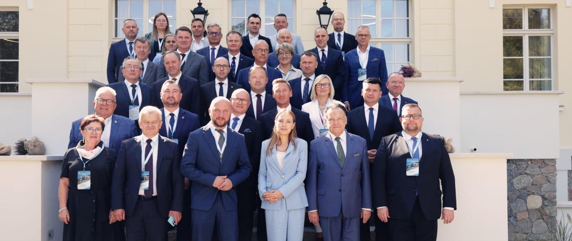 Grupa osób stoi w kilu rzędach na schodach. W pierwszym rzędzie w środku stoi minister Katarzyna Pełczyńska-Nałęcz. 