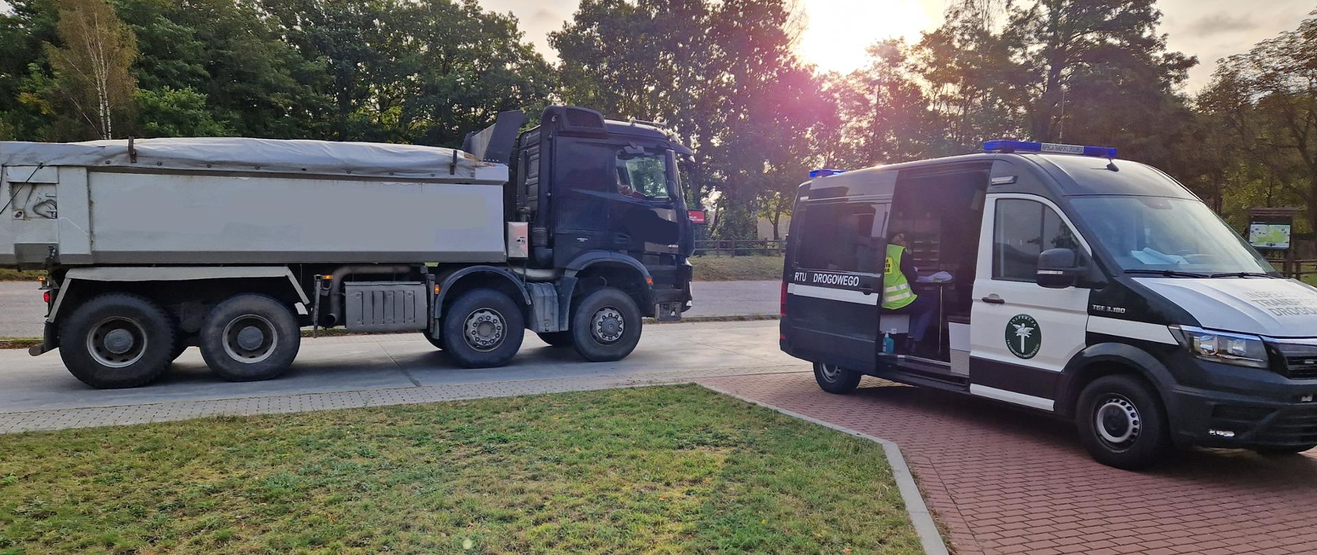 Zatrzymany pojazd ciężarowy podczas kontroli drogowej i stojący obok radiowóz Inspektoratu Transportu Drogowego.