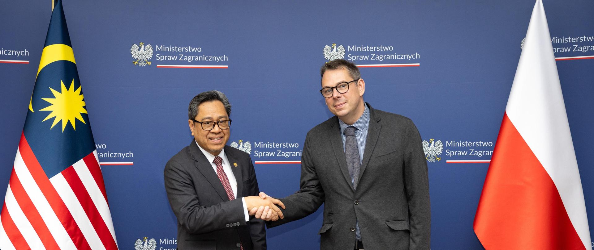 Undersecretary of State Jakub Wisniewski with the Deputy Secretary General of the Malaysian Foreign Ministry, Ahmad Roziani bin Abd. Ghani exchange a handshake against the background of the flags of Poland and Malaysia