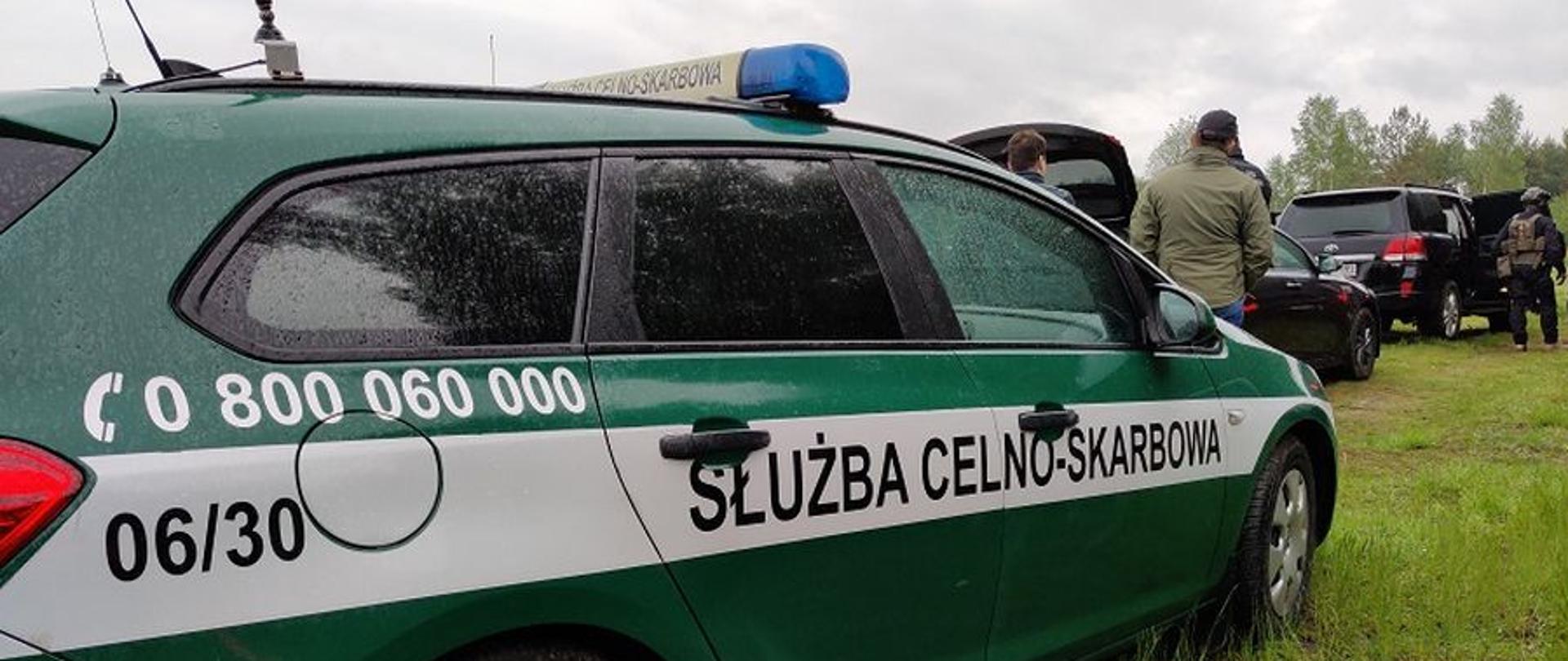 Na pierwszym planie radiowóz Służby Celno-Skarbowej, w głębi inne samochody i funkcjonariusze