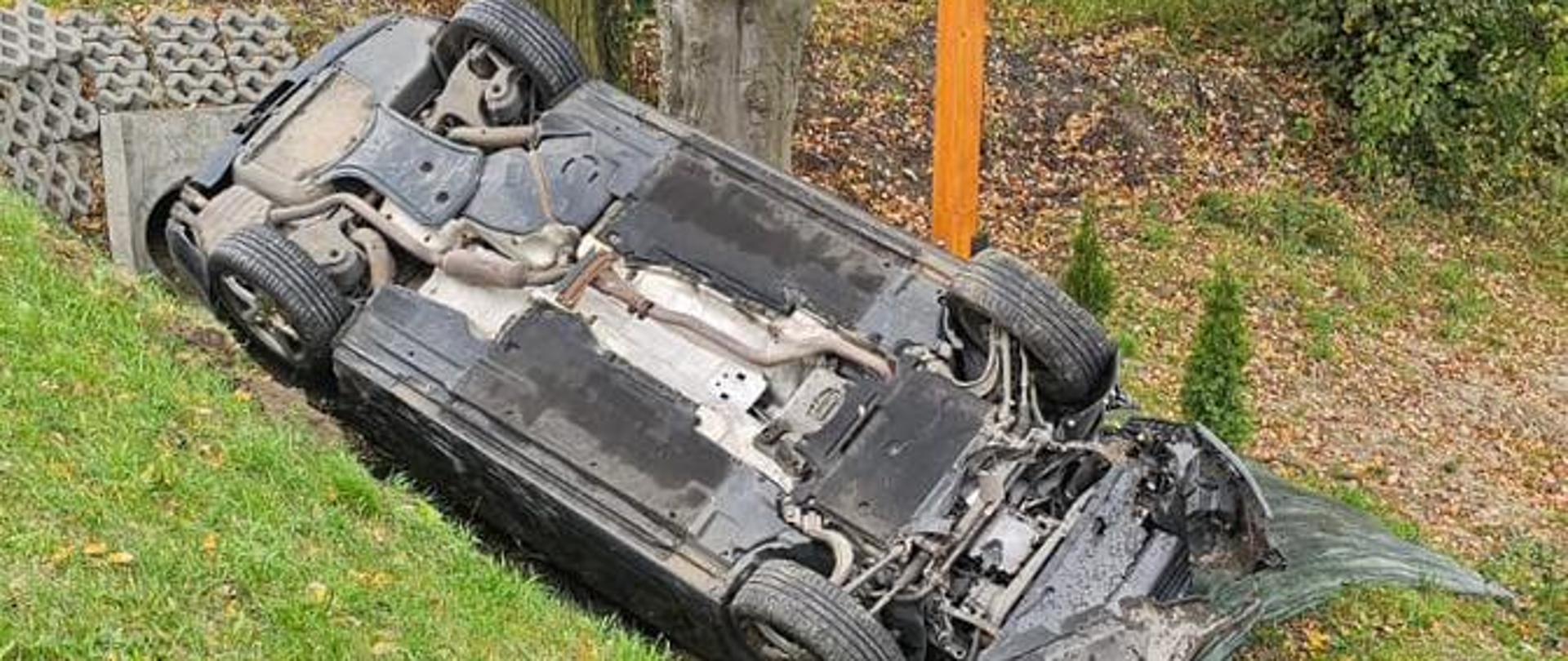 Na zdjęciu widoczny uszkodzony samochód osobowy w rowie na dachu.