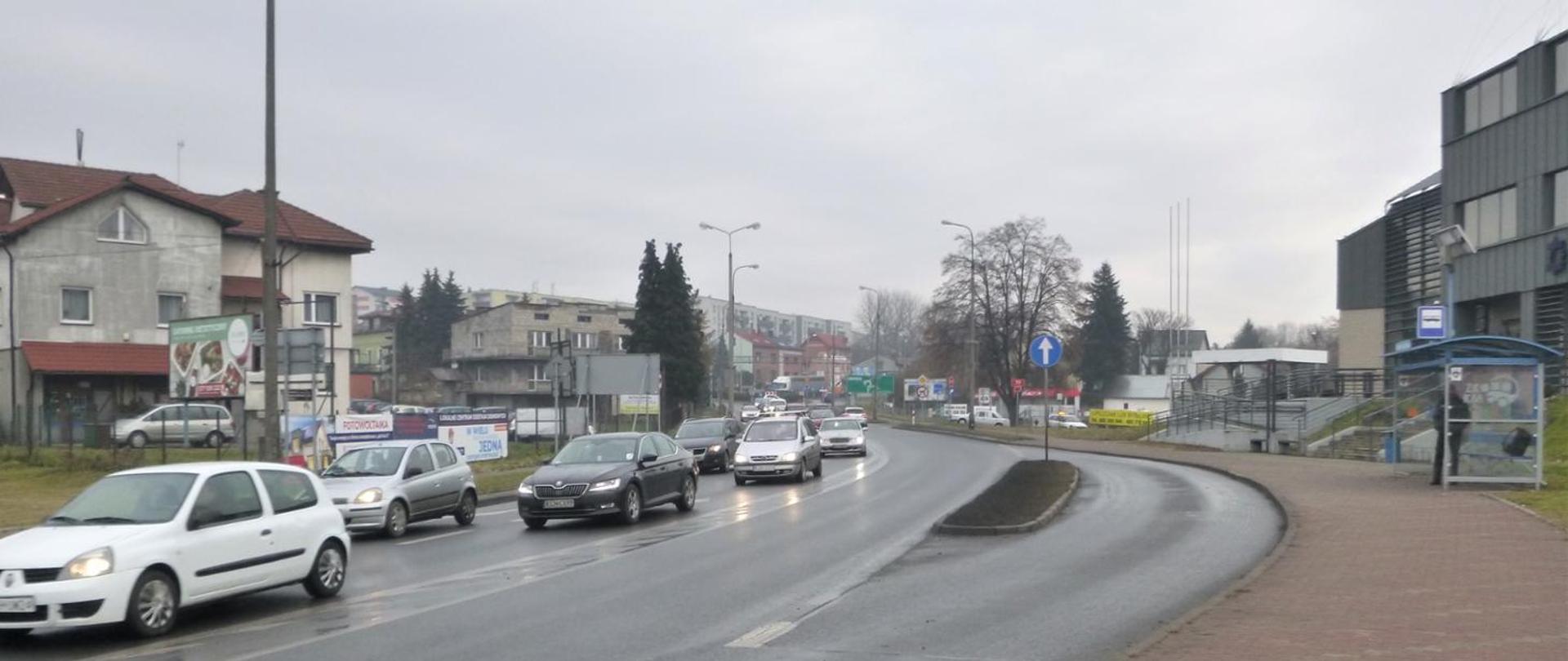 Ruch na zatłoczonej ulicy w mieście, po prawej przystanek komunikacji miejskiej