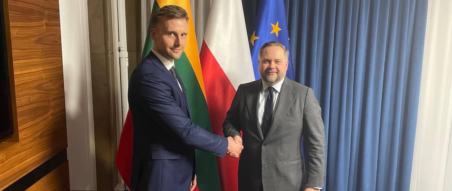 Wiceminister Konrad Gołota oraz wiceminister gospodarki i innowacji Litwy Marius Stasiukaitis stoją na tle flag. 