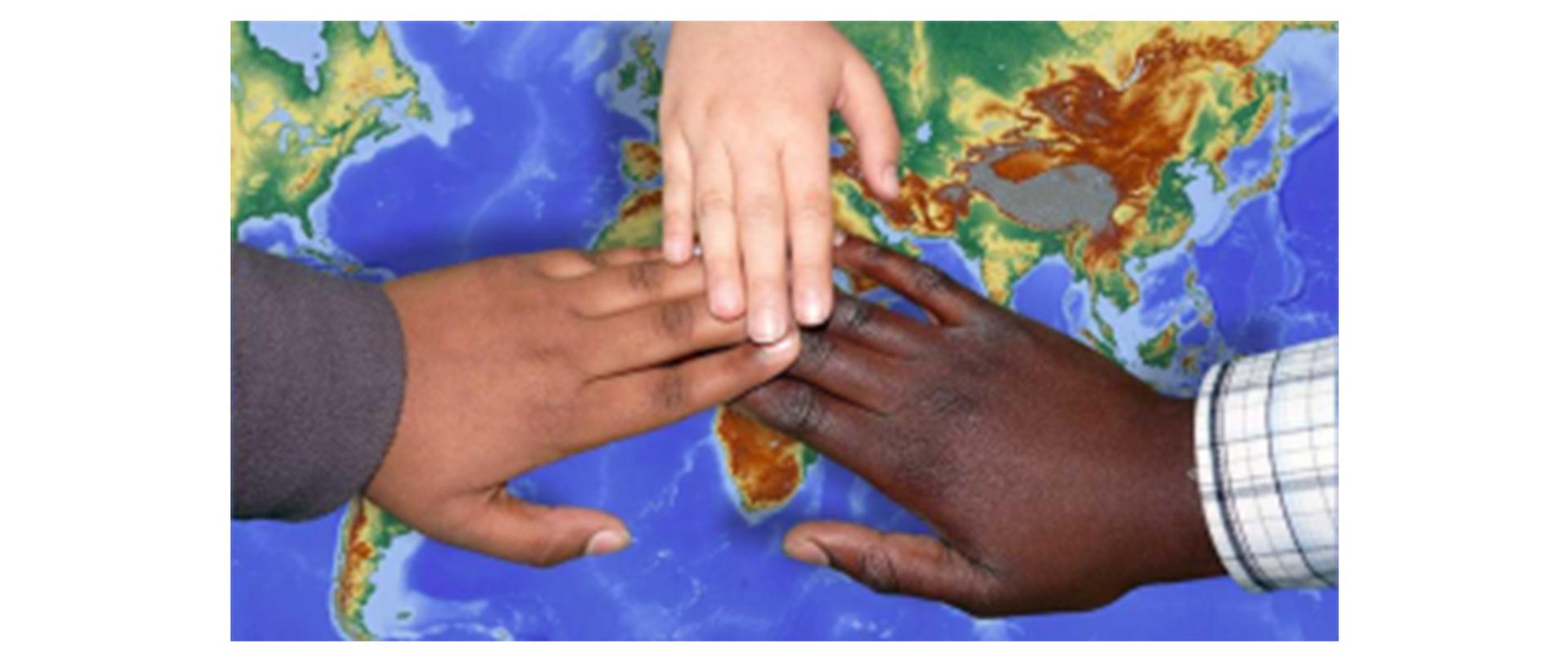 Zdjęcie poglądowe: na tle mapy trzy łączące się dłonie osób o różnych kolorach skóry