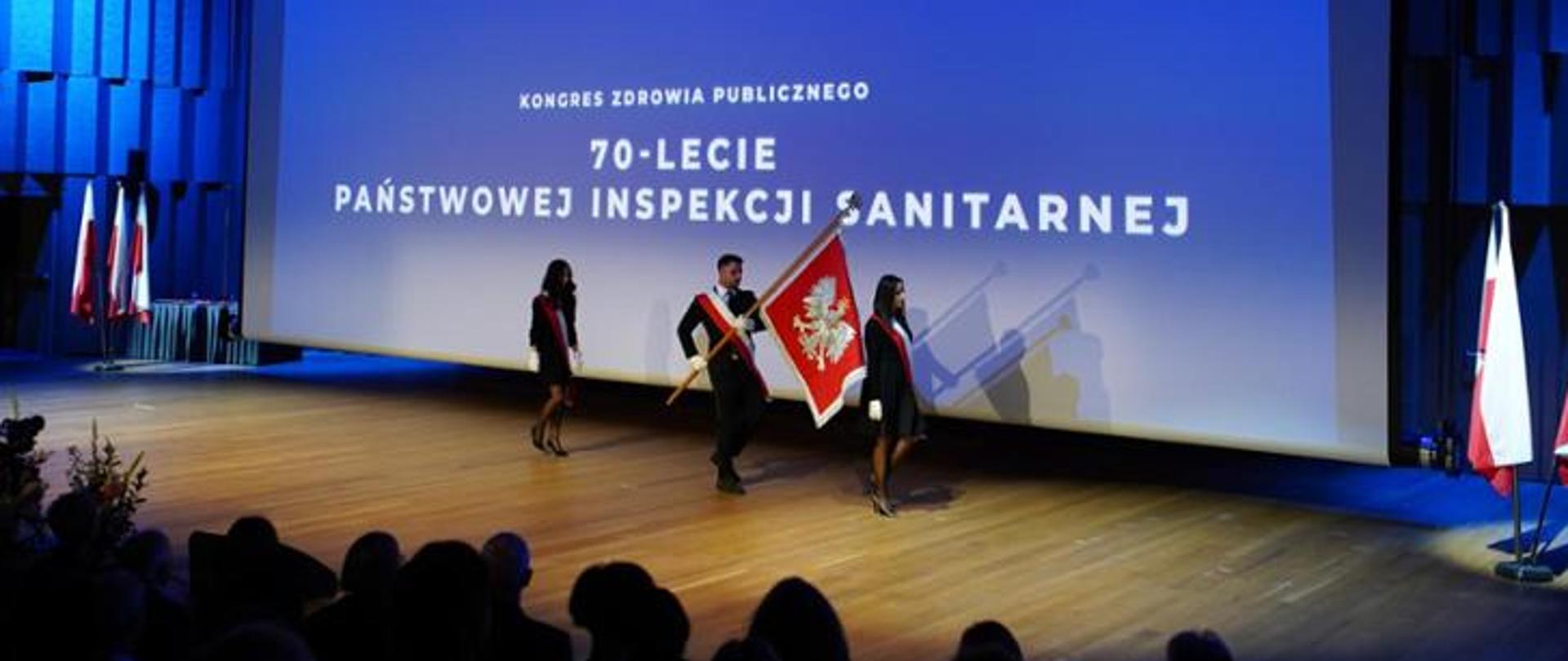 Zdjęcie przedstawia uroczystość 70 lecia Państwowej Inspekcji Saniatarnej- osoby niosące sztandar.