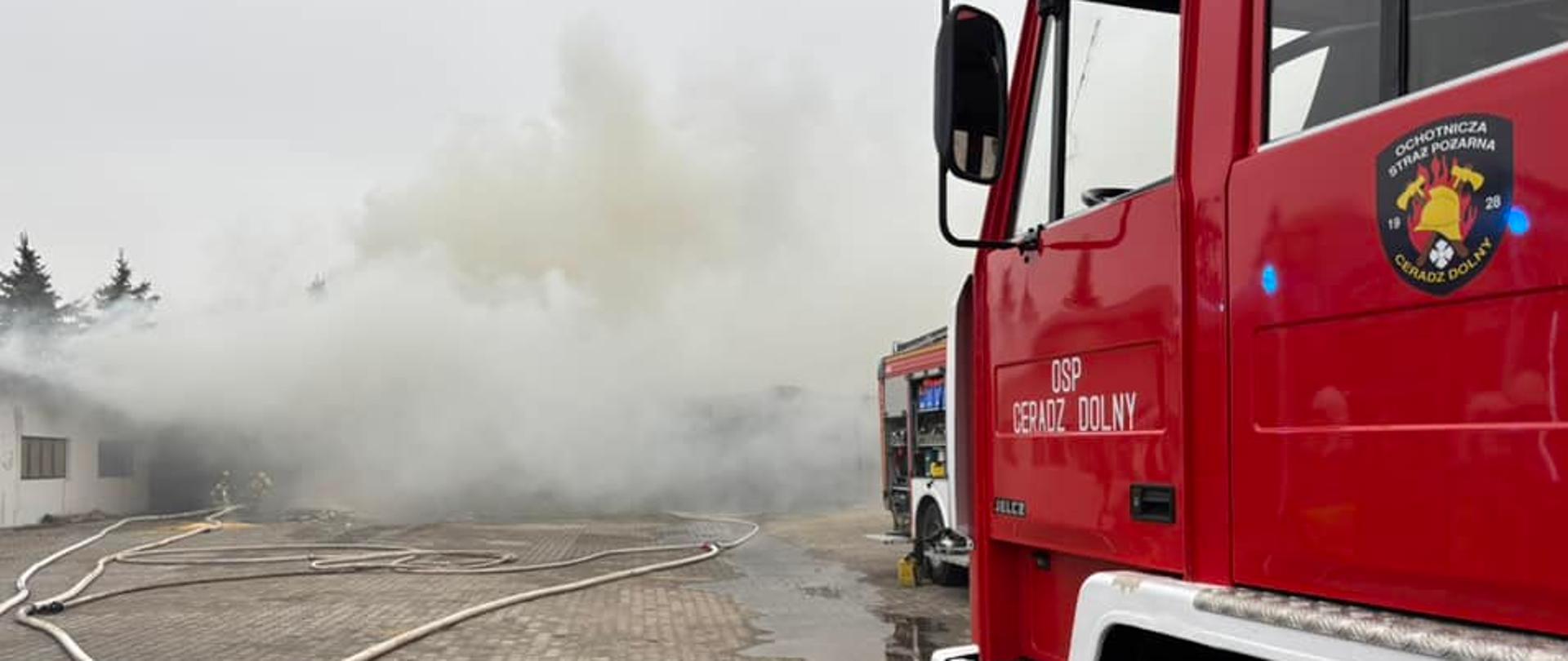 Zadymienie wydobywa się z hali, w pobliżu samochody straży