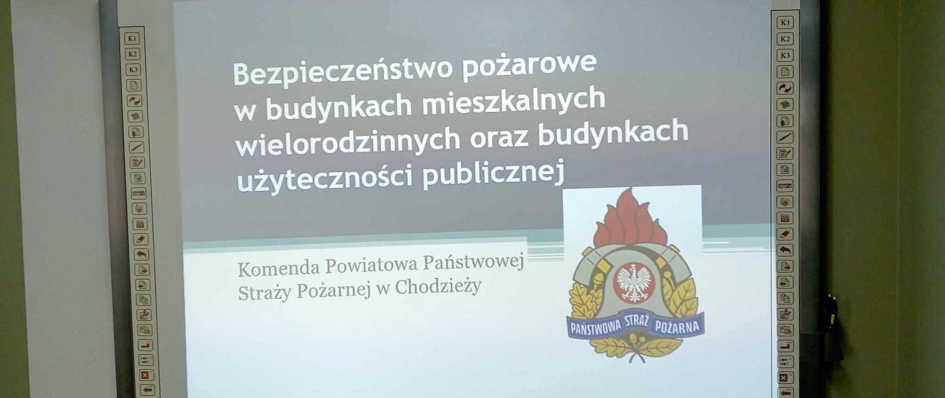 Zdjęcie przedstawia strażaków i przedstawicieli zarządców budynków, którzy wzięli udział w spotkaniu i szkoleniu dotyczącym bezpieczeństwa pożarowego w budynkach. .
W tle pomieszczenie.
