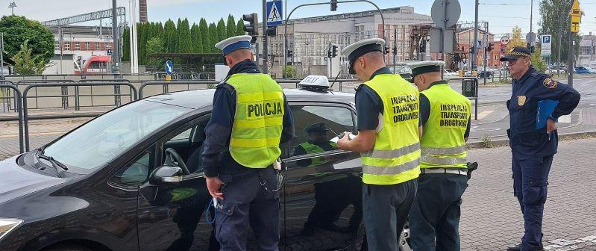 Funkcjonariusze Inspekcji Transportu, Policji i Straży Miejskiej w trakcie kontroli taksówki