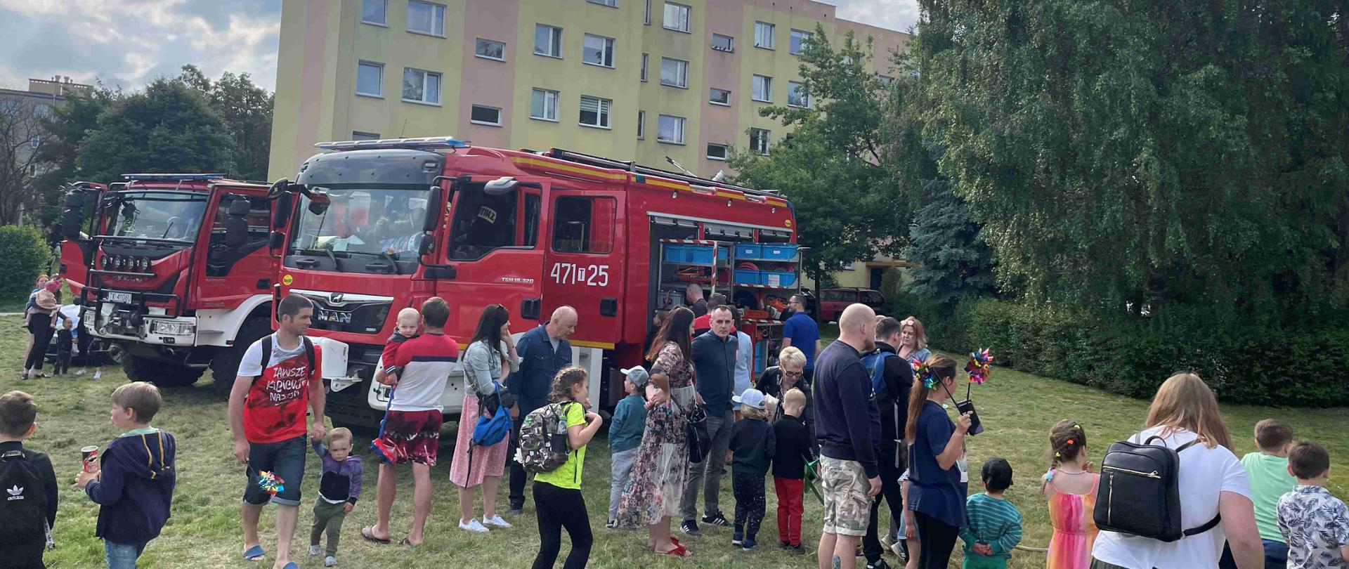 Zdjęcie przedstawia osoby oglądające sprzęt strażacki będący na wyposażeniu samochodów ratowniczo-gaśniczych. 