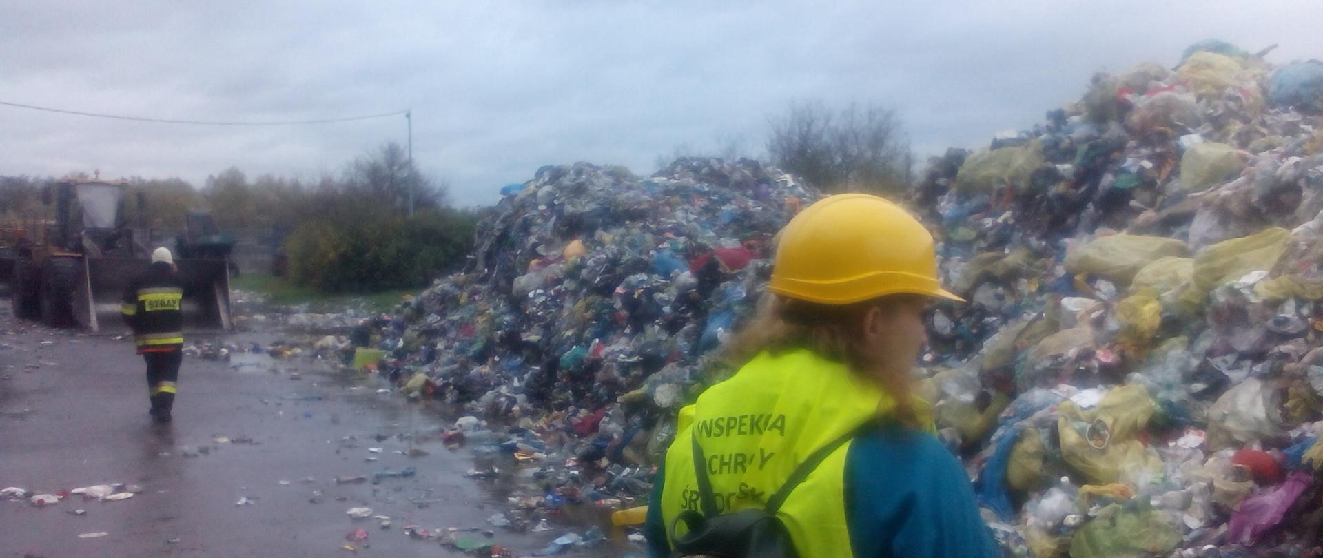 Inspektor Wojewódzkiego Inspektoratu Ochrony Środowiska w Warszawie prowadzi oględziny miejsca wywiezionych z hali odpadów, dogaszonych przez straż.