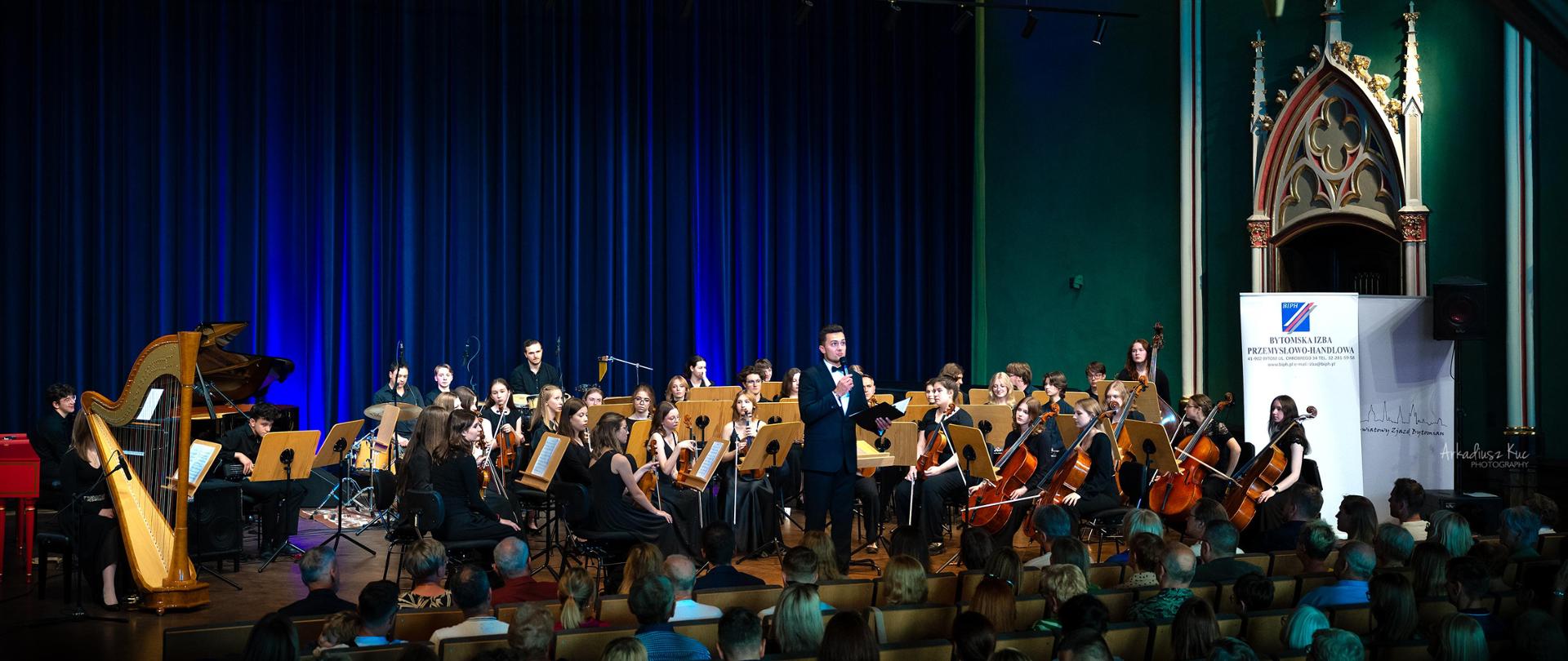 Koncert w sali koncertowej szkoły muzycznej w Bytomiu. Na scenie Polska Młodzieżowa Orkiestra Symfoniczna oraz prowadzący Marcin Gad.
