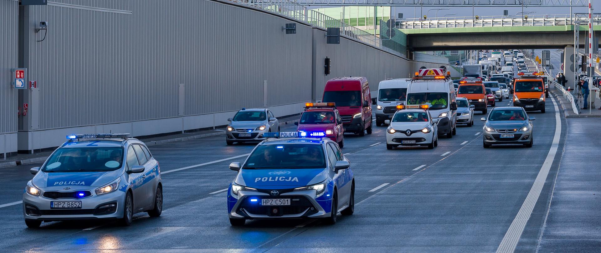 Pierwsze samochody na otwarciu tunelowego odcinka S2 w Warszawie. Na pierwszym planie pojazdy policji, a tuż za nią służby drogowej GDDKiA.