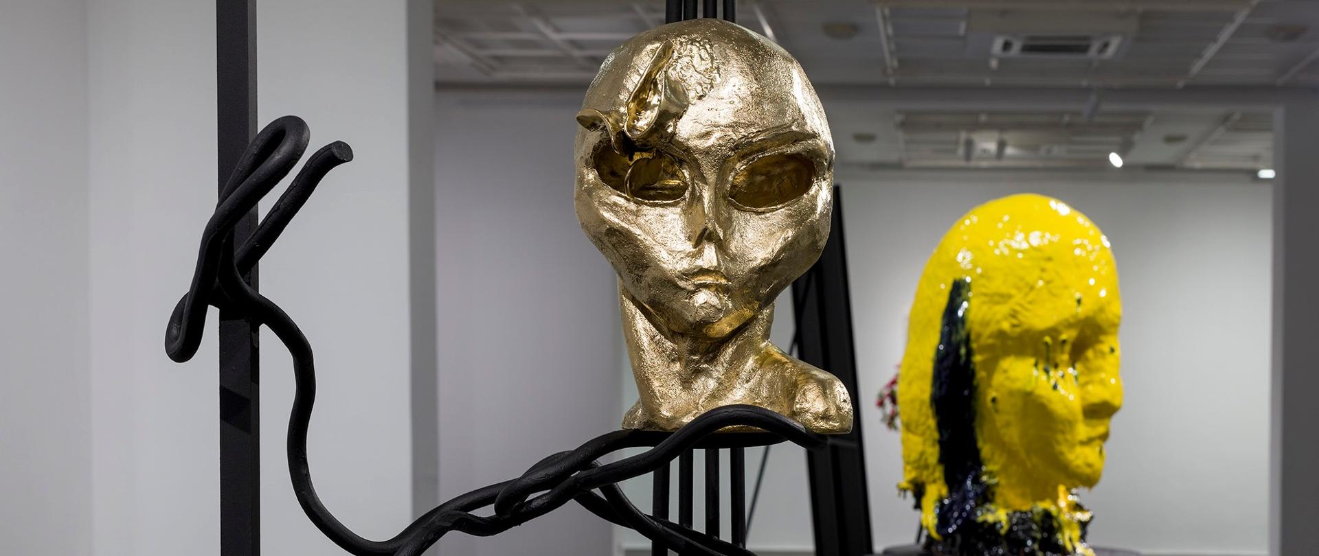 Instalacje artystyczne, głowy postaci podobne do człowieka w kolorze złotym i żółtym