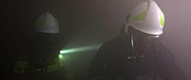 Strażacy OSP w zadymionej ciemnej piwnicy w aparatach OUO.