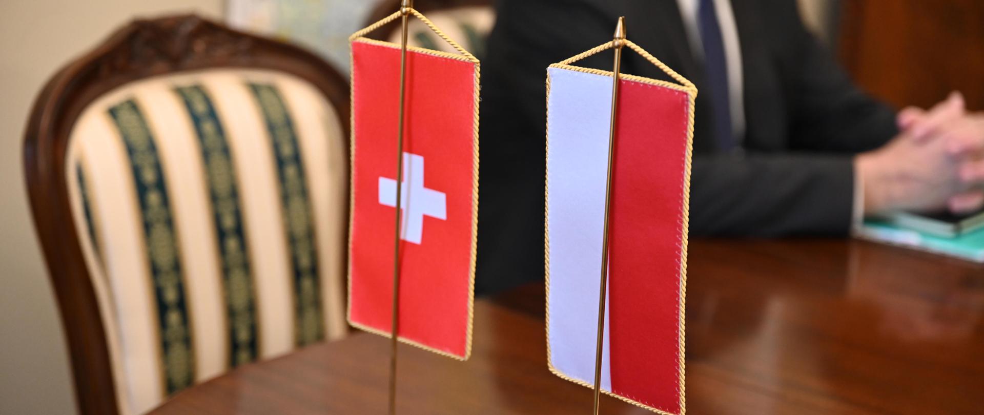 flagi Szwajcarii oraz Polski na stole