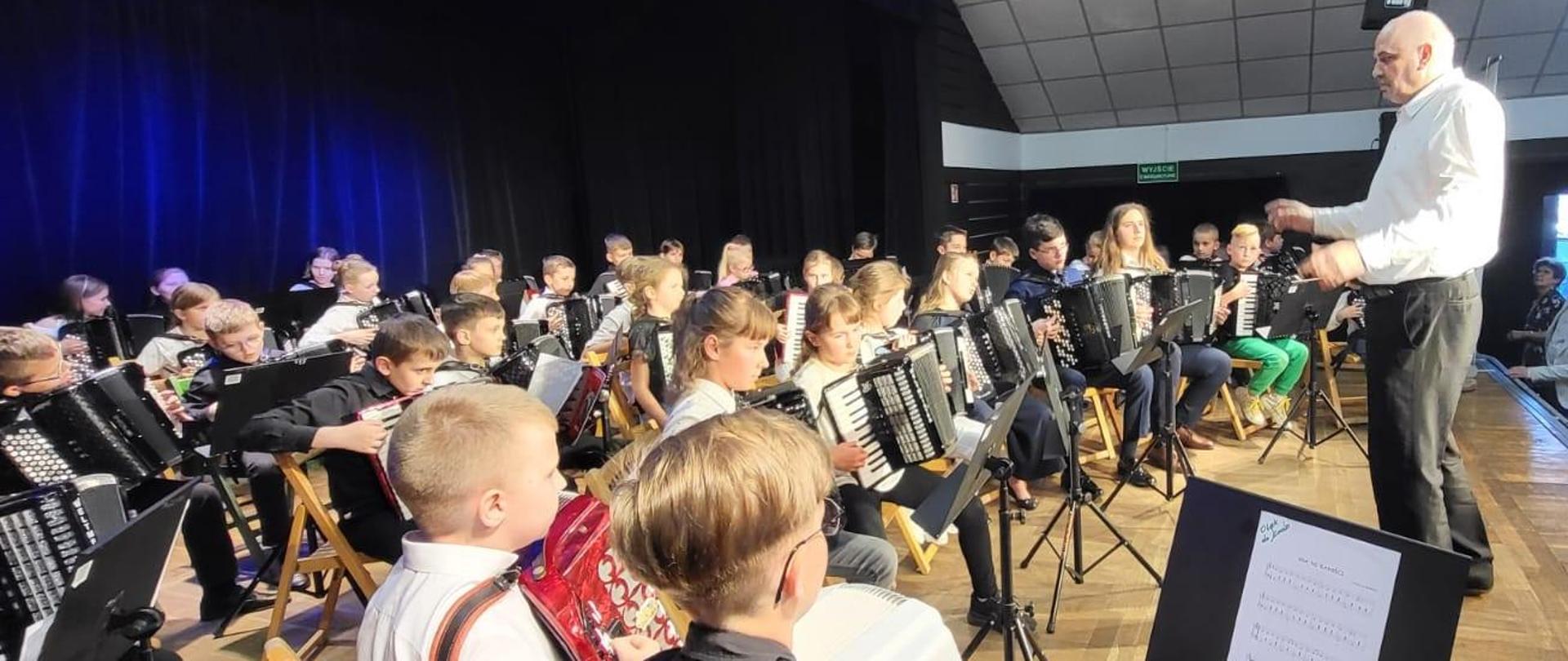 Na zdjęciu grupa kilkudziesięciu młodych akordeonistów, przed nimi stoi dyrygent