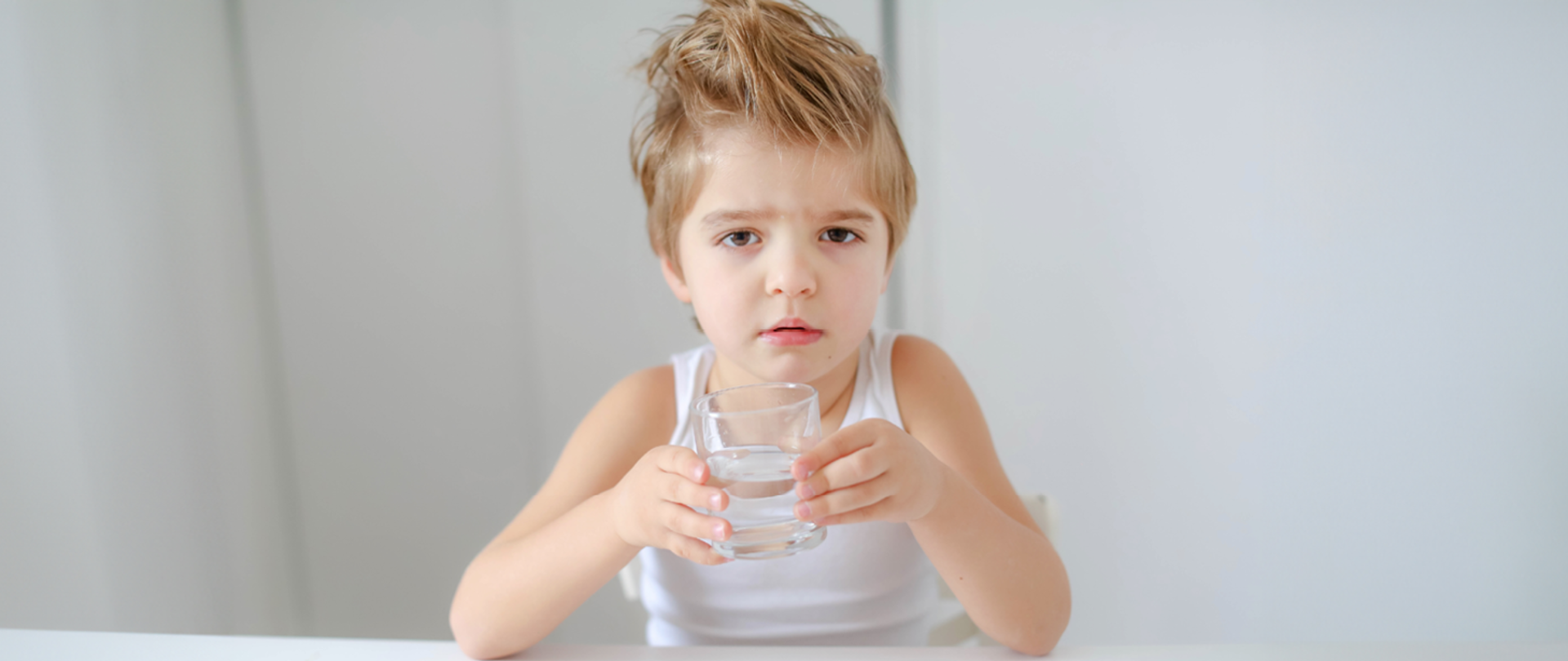 Zdjęcie przedstawi dziecko pijące ze szklanki wodę