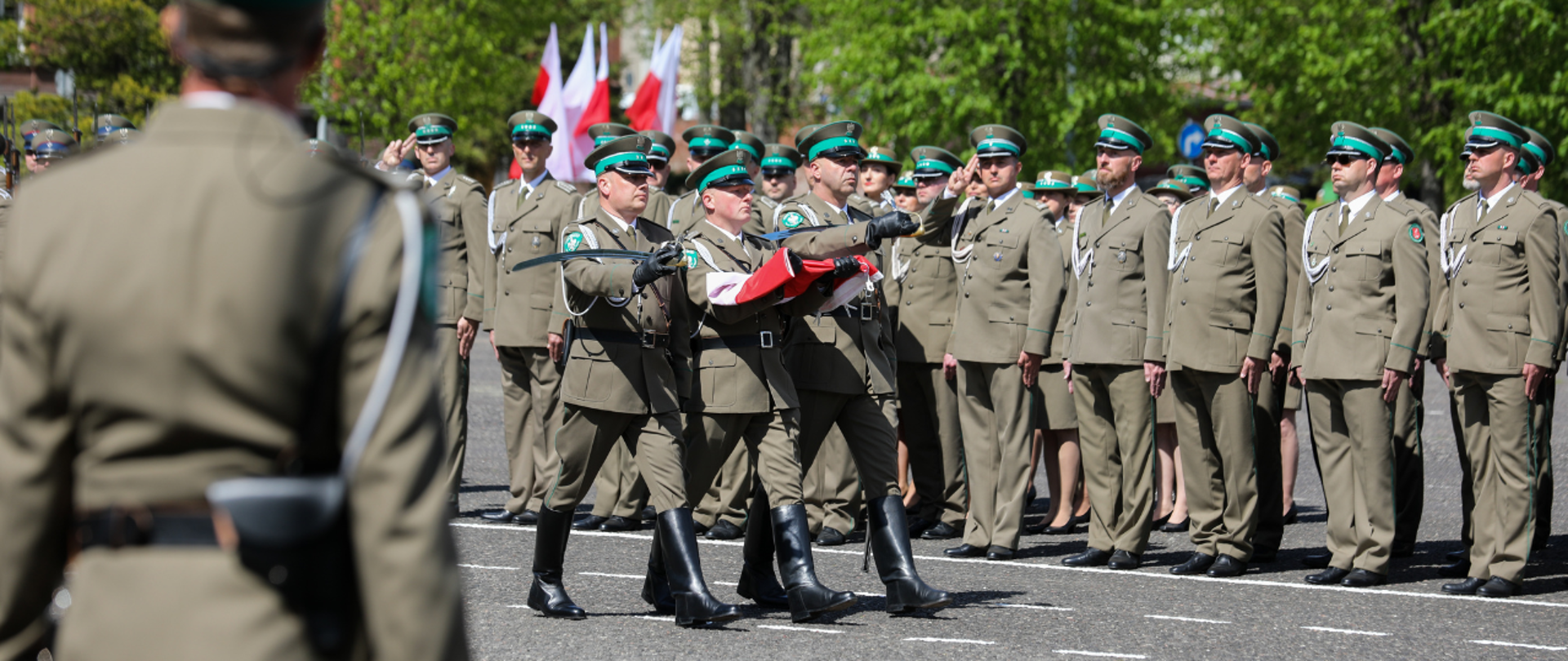 Funkcjonariusze Straży Granicznej niosący flagę Polski.