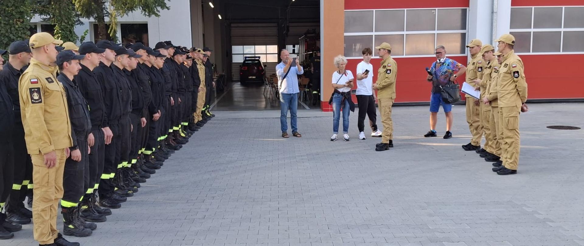 Strażacy stoją w dwuszeregu na przeciw przemawia komendant wojewódzki.