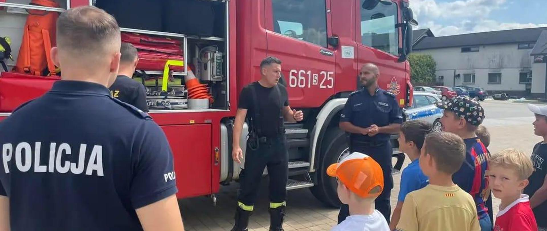 Strażak prezentuje młodzieży wyposażenie samochodu ratowniczego