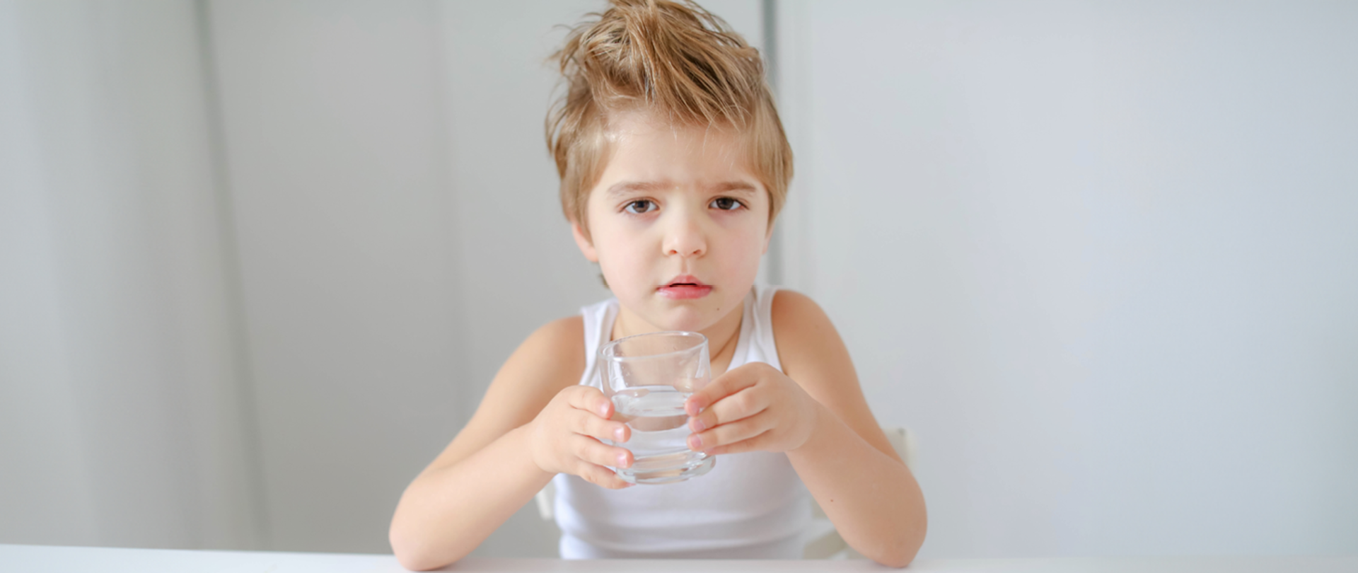 Na zdjęciu znajduje się chłopiec ze szklanką wody