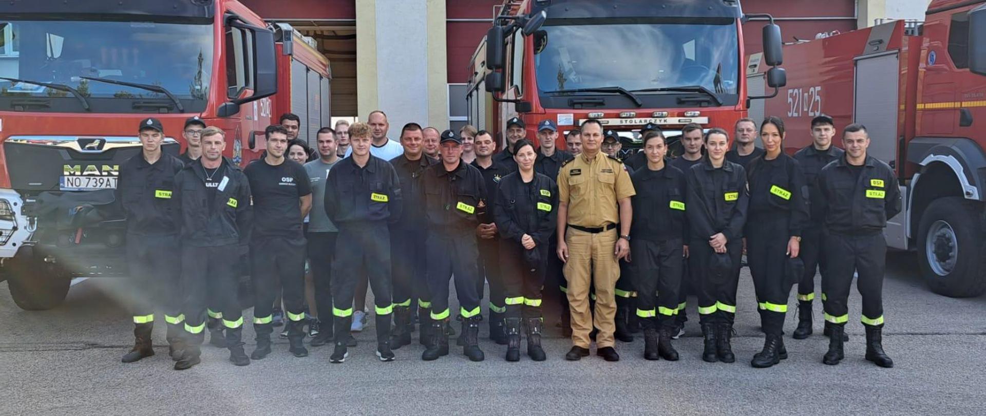 Strażacy na tle Komendy oraz pojazdów JRG