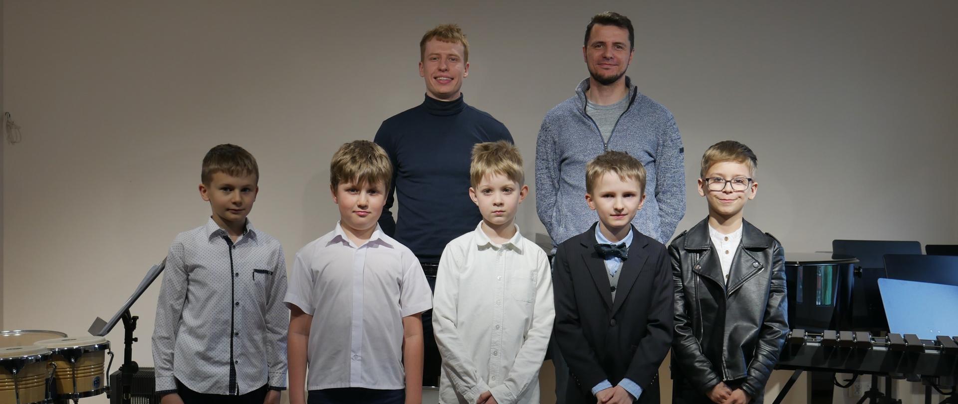 Pięciu chłopców i dwóch nauczycieli stoi na scenie sali kameralnej