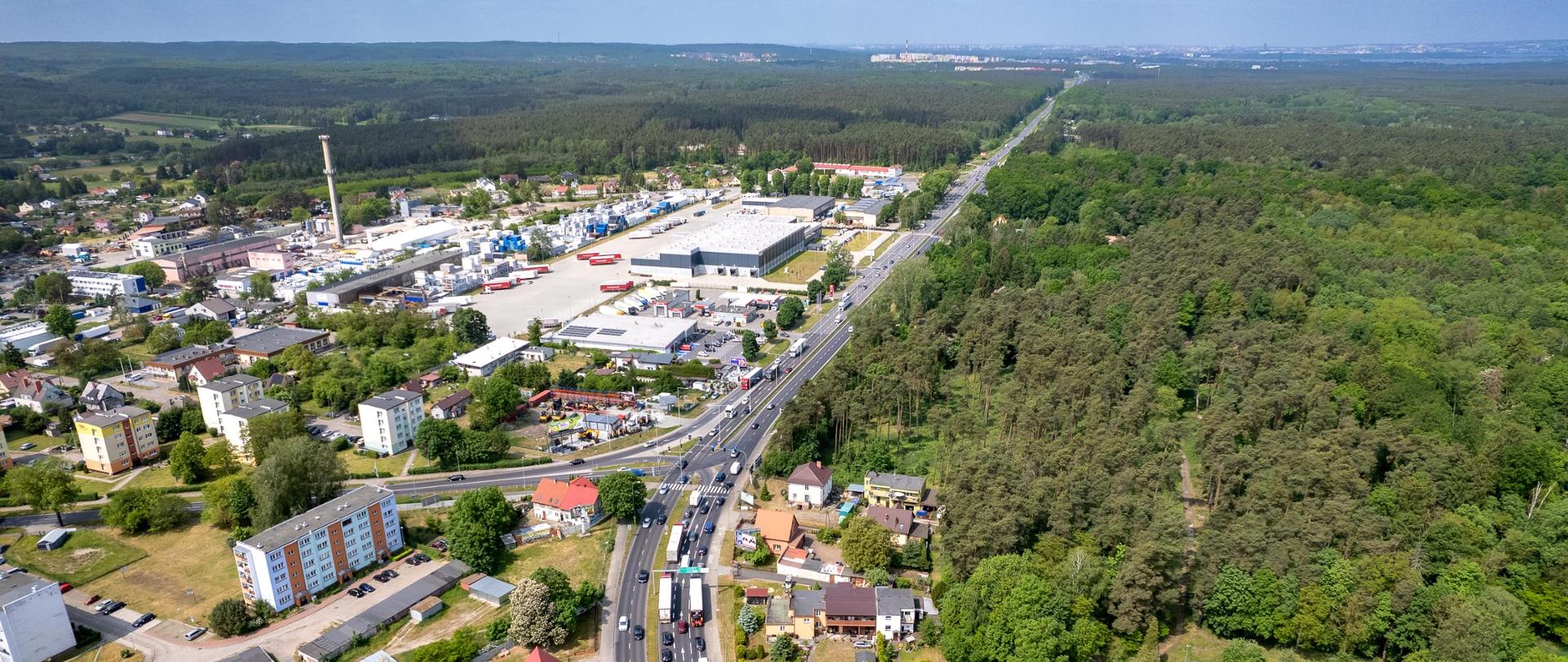 Zdjęcie lotnicze drogi. Widoczne zabudowania oraz w tle duże obszary zalesione.