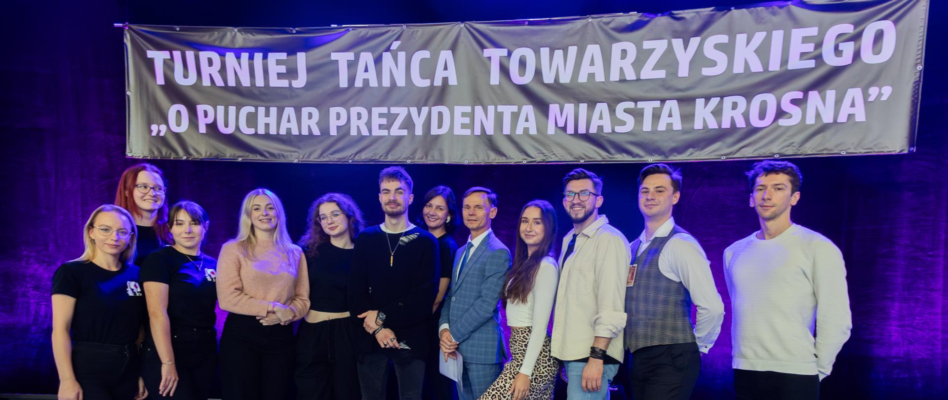 Grupa słuchaczy Studium stojący na tle banneru z napisem Turniej tańca towarzyskiego o Puchar Prezydenta Miasta Krosna.