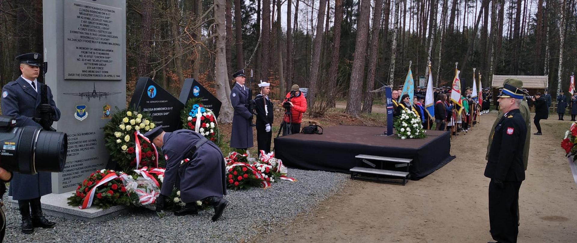 Na zdjęciu widać, żołnierza składającego bukiet kwiatów pod pomnikiem.