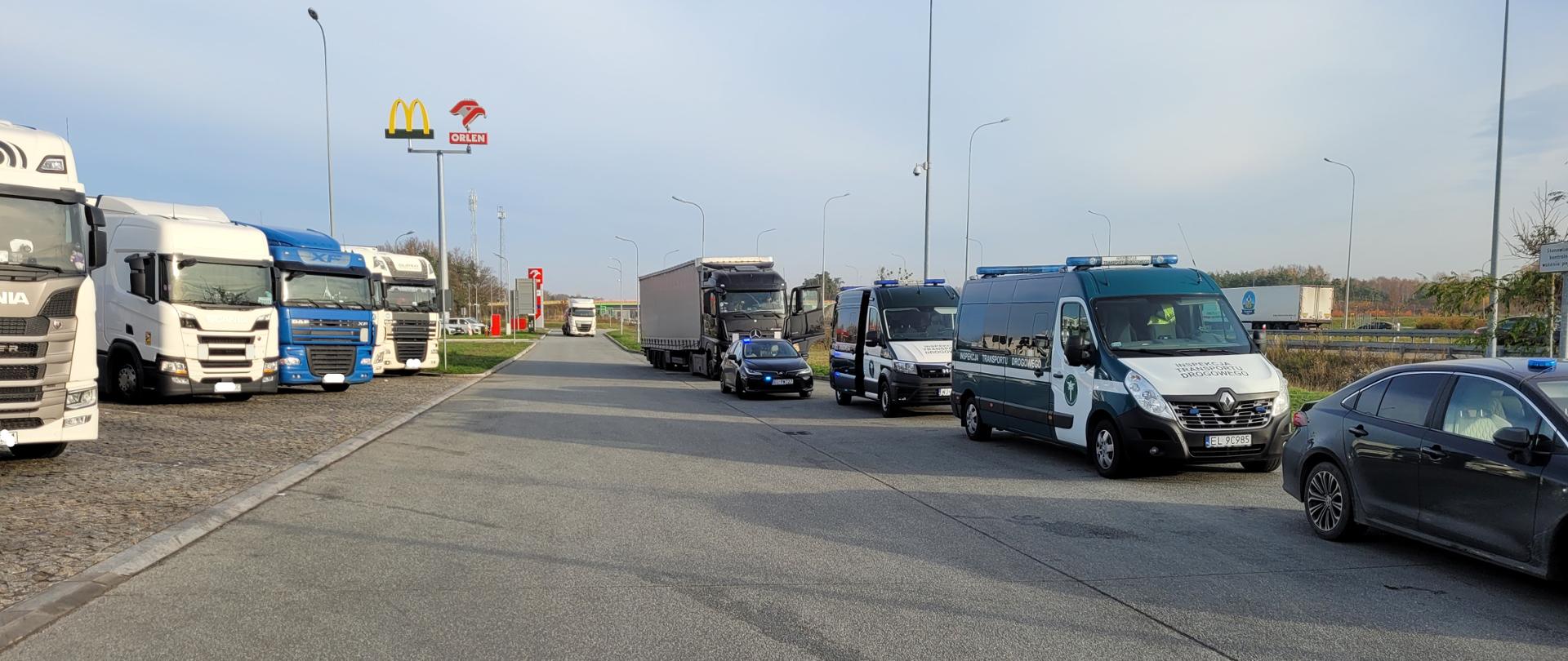 Pojazdy ciężarowe i radiowozy ITD na parkingu MOP